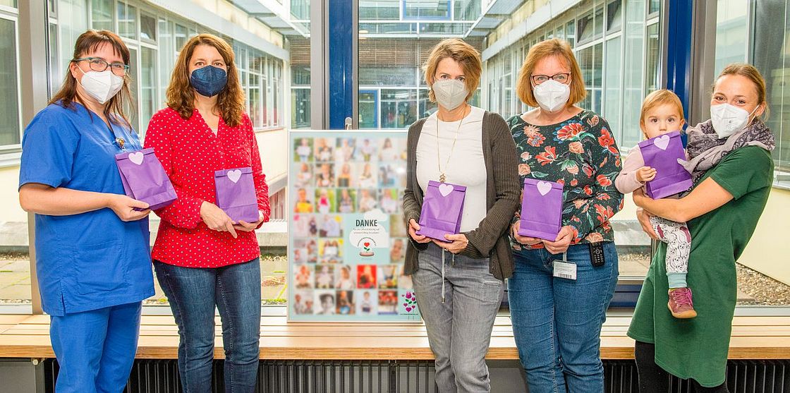 Das Bild zeigt Kerstin Klein, Antje Rinaldi, Ines Dombrowski, Petra Schlömer (Stationsleitung S25) und Janina Schmidt mit Kind bei der Geschenkeübergabe (v.l.n.r.)