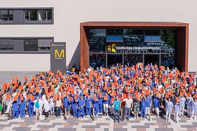 Das Bild zeigt Mitarbeitende des Klinikums Karlsruhe vor dem Gebäude mit roten Karten