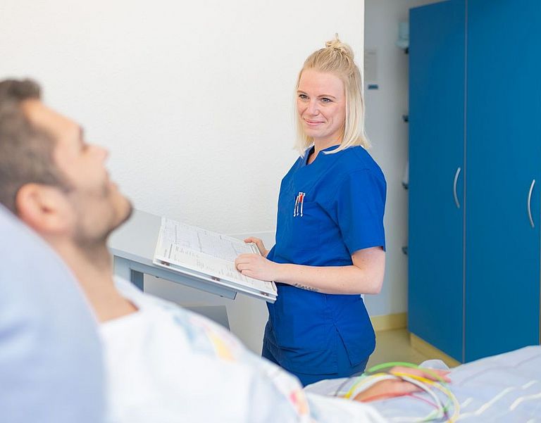 Das Bild zeigt eine Pflegefachkraft im Gespräch mit einem Patienten