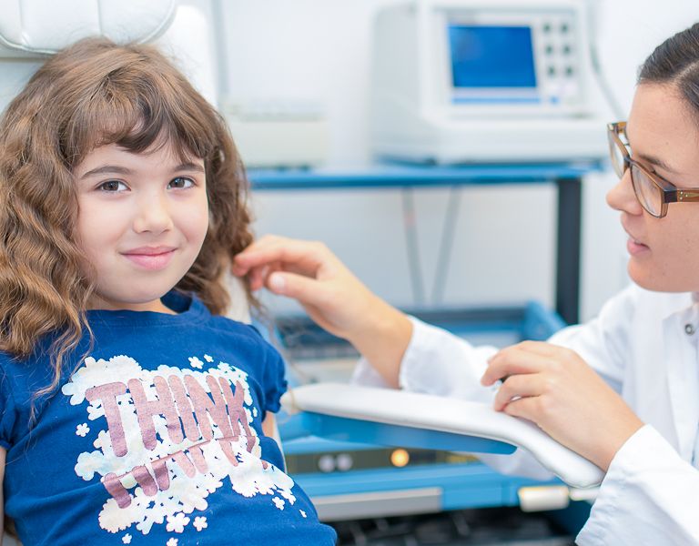 Das Bild zeigt ein Kind und eine Ärztin bei einer HNO-Untersuchung
