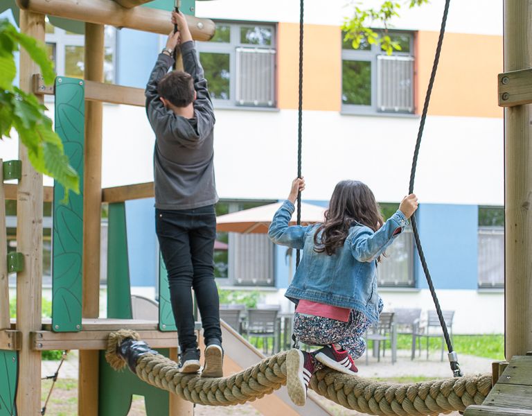 Das Bild zeigt zwei Kinder auf einem Kinderspielplatz