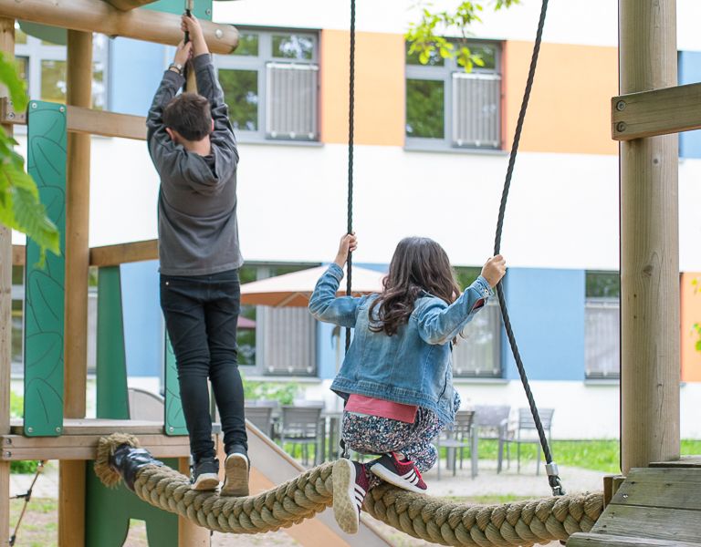 Das Bild zeigt zwei Kinder auf einem Kinderspielplatz