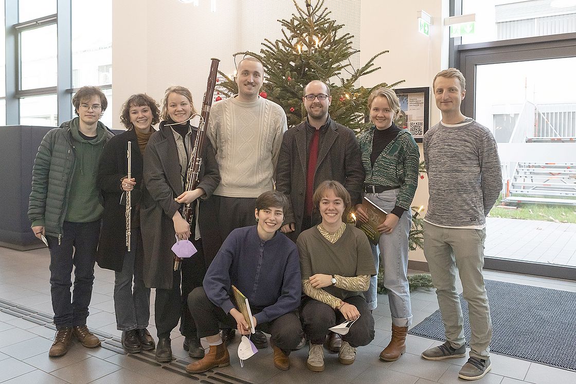 Das Bild zeigt 9 Musiker*innen des EnsembleVokal Karlsruhe im Eingangsbereich von Haus M.