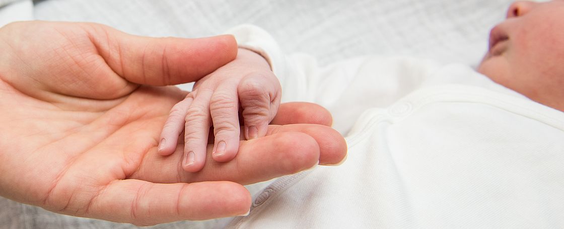 Das Bild zeigt eine Neugeborenenhand in einer Erwachsenenhand