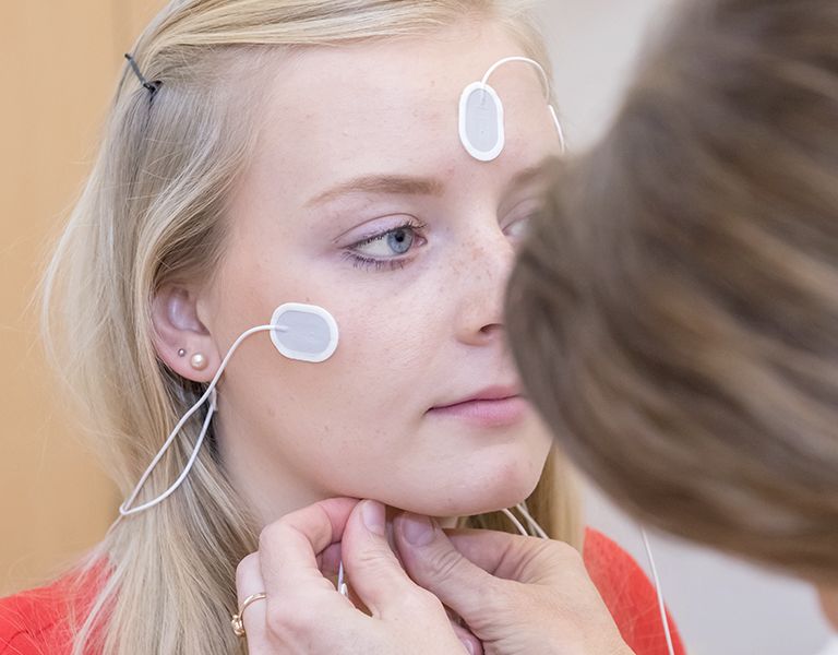 Das Bild zeigt die Verkabelung einer Patienten mit Elektroden am Kopf und-Stirnbereich