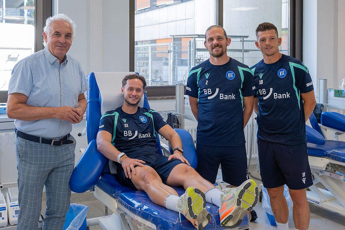 Das Bild zeigt Priv.-Doz. Dr. Andreas Ruf mit KSC-Profis Christoph Kobald, Sebastian Jung und Marvin Wanitzek.