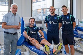 Das Bild zeigt Priv.-Doz. Dr. Andreas Ruf mit KSC-Profis Christoph Kobald, Sebastian Jung und Marvin Wanitzek.