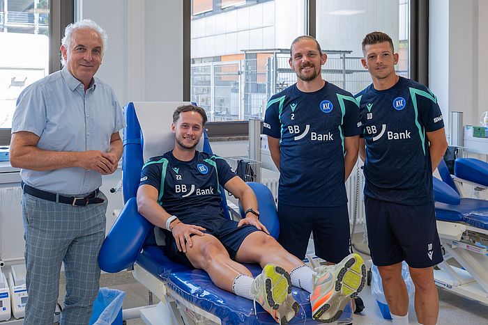 Das Bild zeigt Priv.-Doz. Dr. Andreas Ruf mit KSC-Profis Christoph Kobald, Sebastian Jung und Marvin Wanitzek.