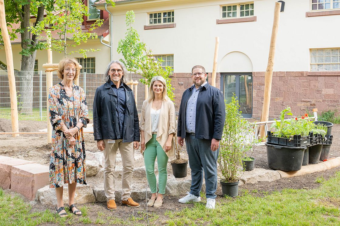 Das Foto zeigt ein Gruppenbild mit vier Personen auf dem Ausßengelände der KiTA "Klinikzwerge" anlässlich der Spendenübergabe durch die FirmaFielmann