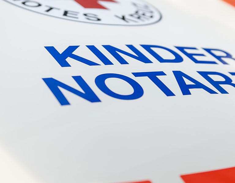 Das Bild zeigt die Aufschrift "Kindernotarzt" auf der Motorhaube des Kindernorarztwagens.