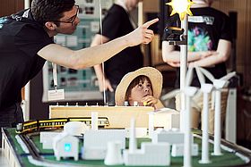 Das Bild zeigt einen Mann und einen Jungen, die ein Experiment beobachten.