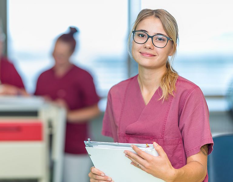 Das Bild zeigt eine Gesundheits- und Krankenpflegerin mit Patientenakte