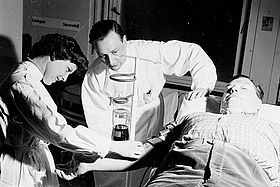 Das Bild zeigt Dr. Heinz Merkel (Mitte), der neben seiner Tätigkeit als Anästhesist auch Leiter der Blutbank war (Foto von 1955). 