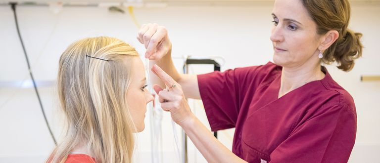 Das Bild zeigt eine Medizinische Fachangestellte bei der Verkabelung einer Patientin.