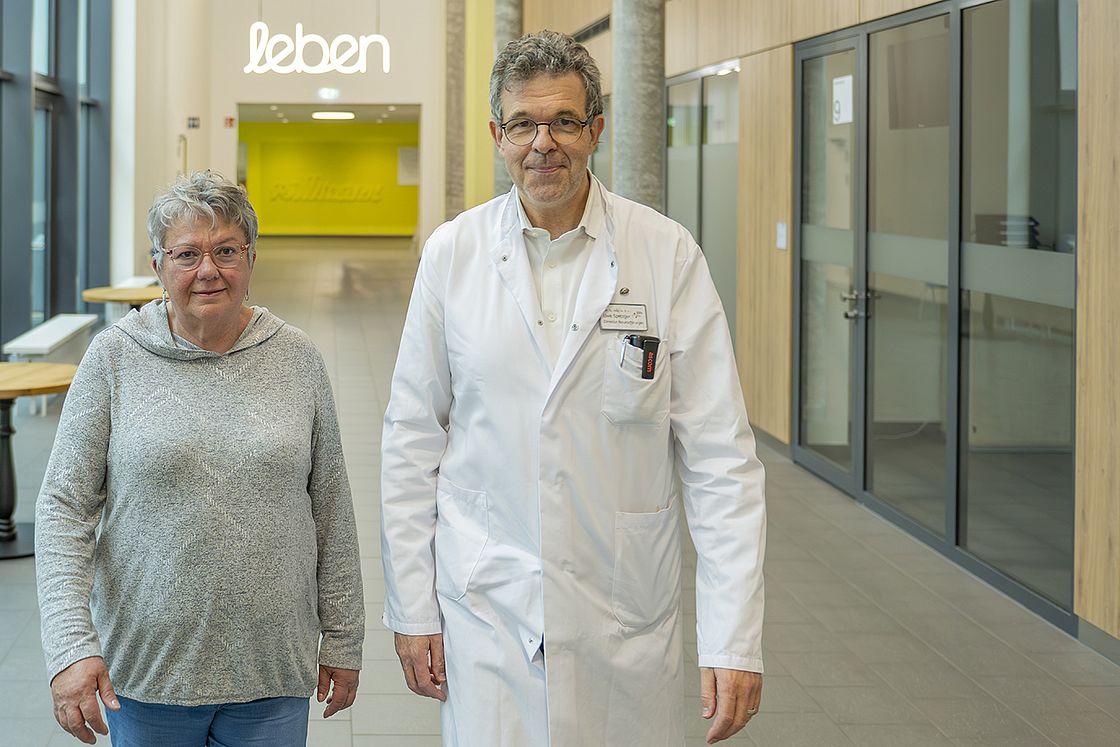 Das Bild zeigt Raymonde Roesch und Prof. Uwe Spetzger in der Eingangshalle von Haus M des Klinikums Karlsruhe.