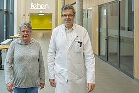 Das Bild zeigt Raymonde Roesch und Prof. Uwe Spetzger in der Eingangshalle von Haus M des Klinikums Karlsruhe.