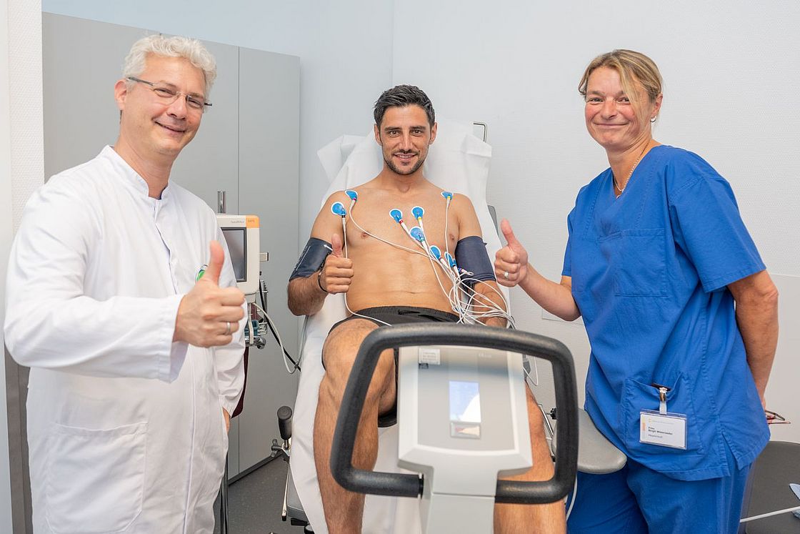 Das Bild zeigt Prof. Julian Widder, Lars Stindl und Birgit Wienroeder (v.l.n.r.) während der Untersuchung