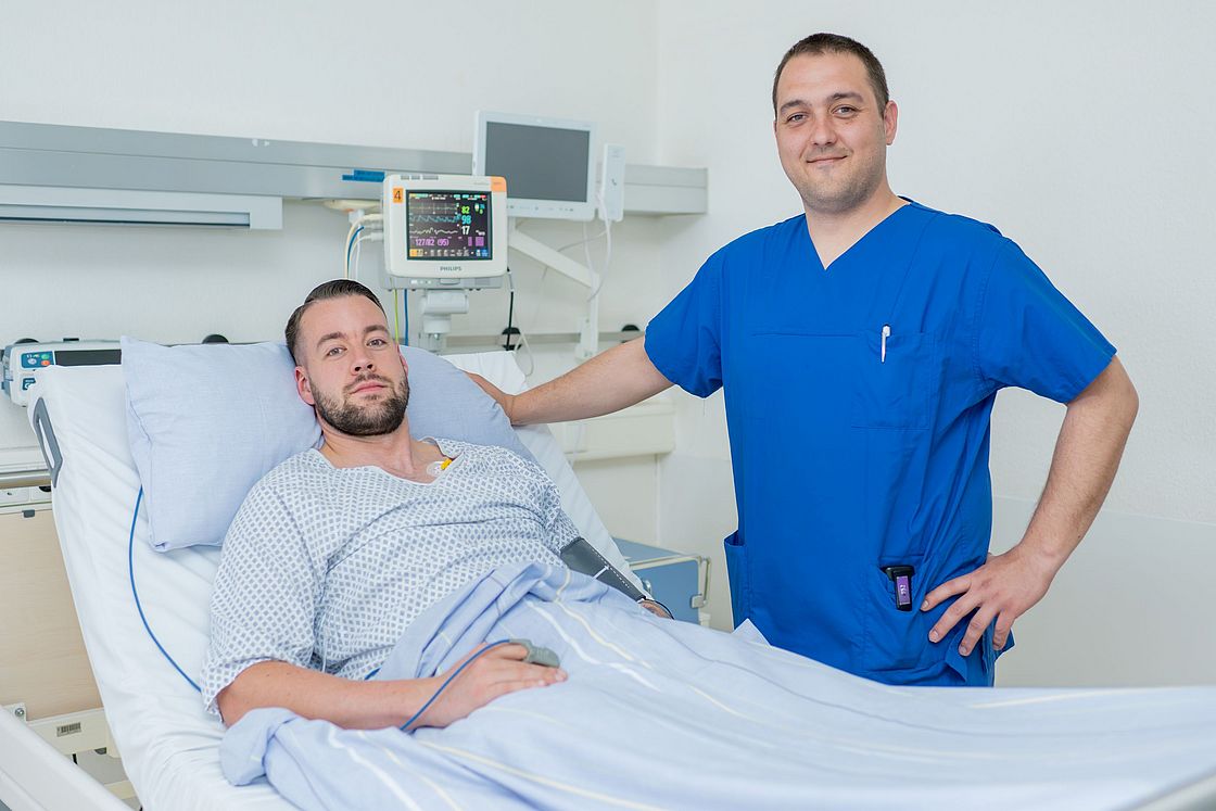Das Bild zeigt Milan Kusic am Bett eines Patienten.