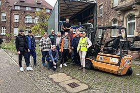 Das Bild zeigt ein Gruppenbild der Unterstützerinnen und Unterstützer der Bettenspende für die Ukraine. die Personen sehen vor dem LKW, der die Materialien in die Ukraine bringt. Im Hintergrund der Altbau Haus C des Klinikums.