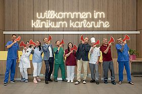 Das Bild zeigt verschiedene Berufsgruppen mit Megafonen