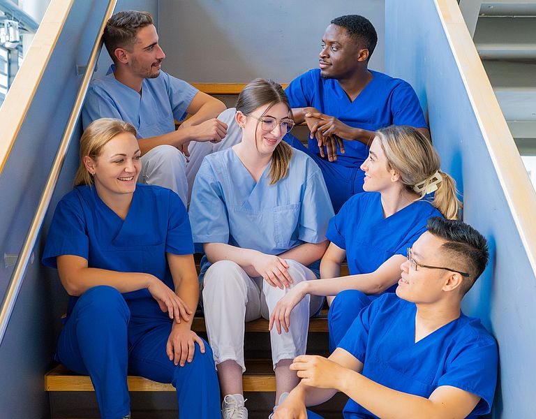 Das Bild zeigt eine Gruppe junger Menschen, die auf einer Treppe sitzt.