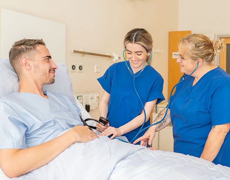 Das Bild zeigt eine Anleitesituation am Patientenbett.