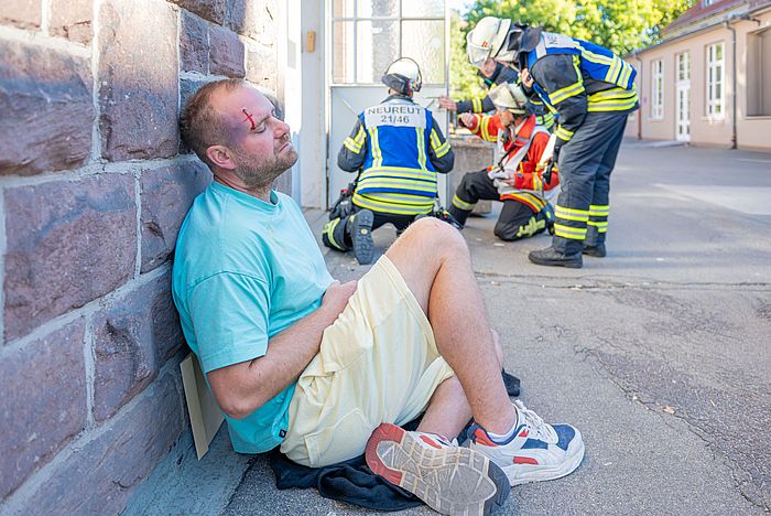Ein Statist sitzt vor der verrauchten Heizzentrale. 