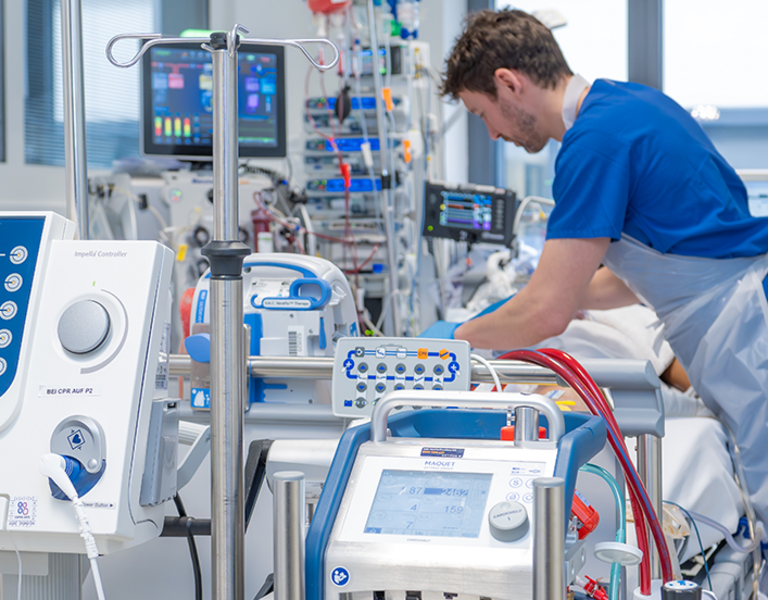 Das Bild zeigt einen Ausschnitt der Versorgung auf einer Intensivstation. Zu sehen ist im Vordergrund eine ECMO.