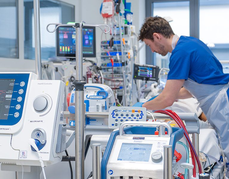 Das Bild zeigt einen Ausschnitt der Versorgung auf einer Intensivstation. Zu sehen ist im Vordergrund eine ECMO.