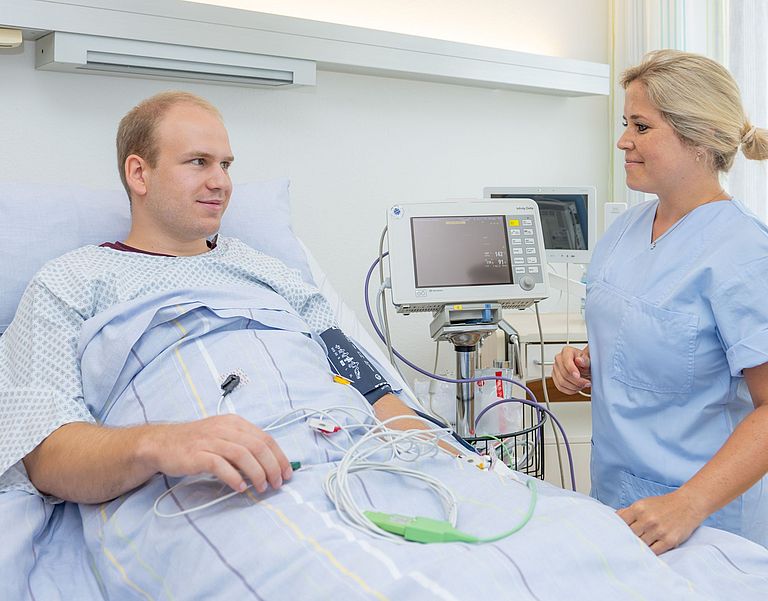 Das Bild zeigt eine Pflegefachkraft und einen Patienten bei der Erstellung eines EKG.