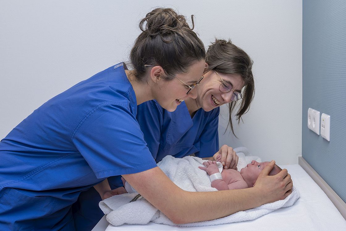 Das Bild zeigt Hebammen, die ein Neugeborenes versorgen