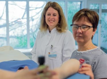 Das Bild zeigt drei Frauen, die den Patienten zur Bestrahlung vorbereiten.