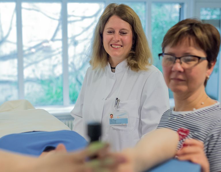 Das Bild zeigt drei Frauen, die den Patienten zur Bestrahlung vorbereiten.