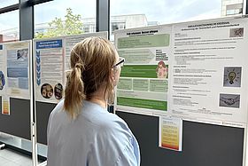 Das Bild zeigt eine Pflegekraft, die wissenschaftliche Plakate betrachtet.