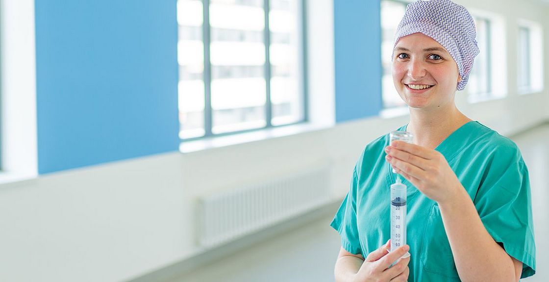 Das Bild zeigt eine junge Frau in OP-Kleidung mit einer Spritze in der Hand.