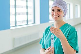 Das Bild zeigt eine junge Frau in OP-Kleidung mit einer Spritze in der Hand.