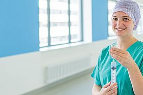 Das Bild zeigt eine junge Frau in OP-Kleidung mit einer Spritze in der Hand.