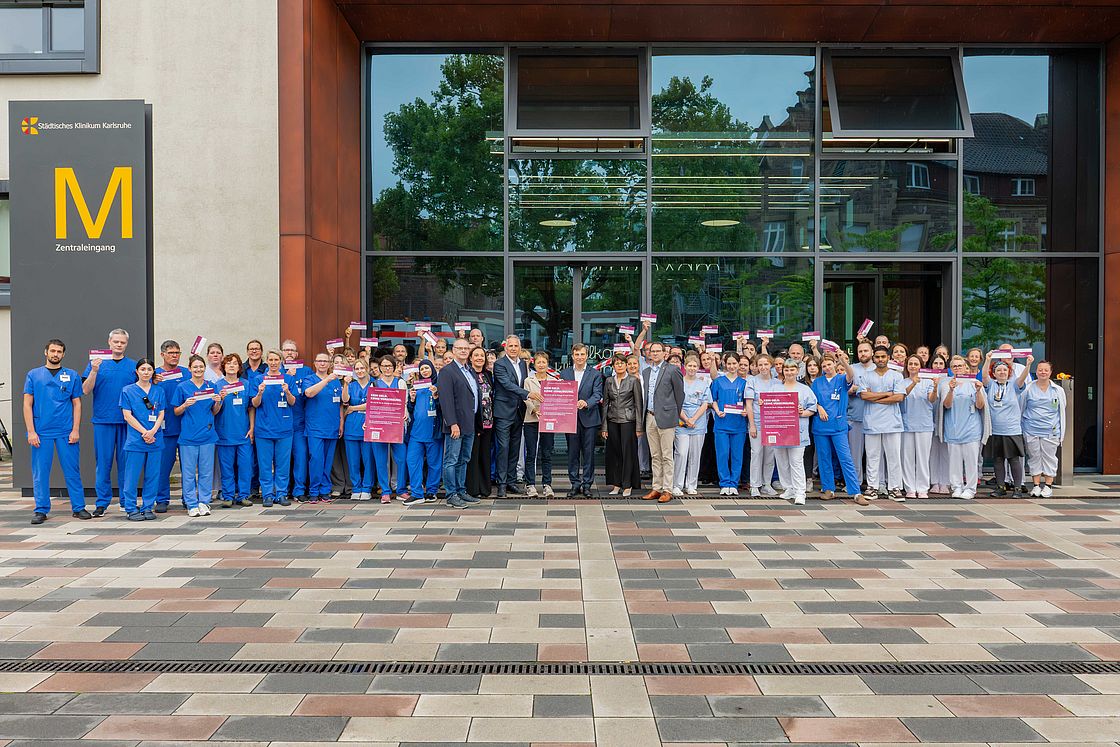 Das Bild zeigt Mitarbeitende der Klinikums Karlsruhe vor der verschlossenen Tür.