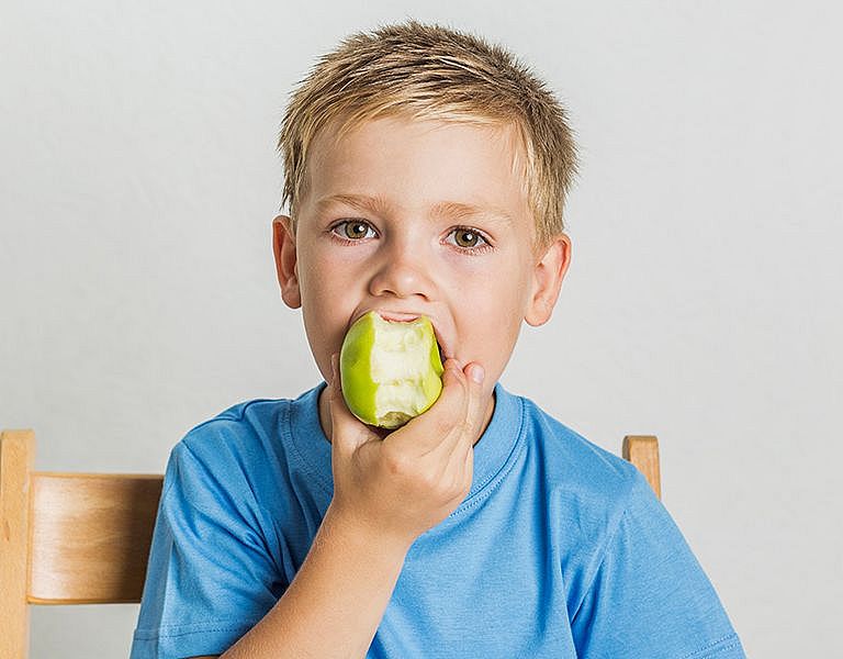Ein Kind beißt in einen Apfel.