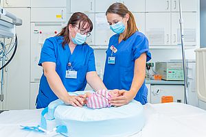 Kerstin Klein und Charlotte Arlt demonstrieren die Funktion des Stillkissens an einer Frühchen-Puppe