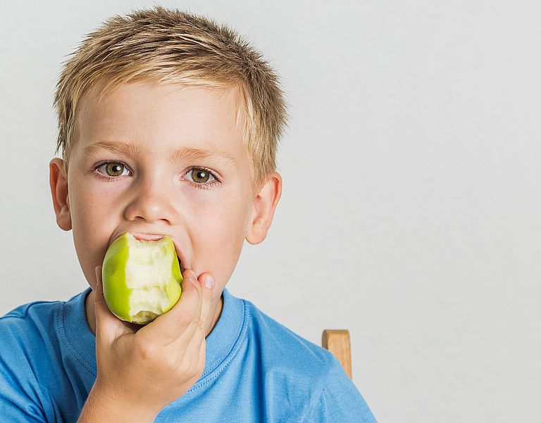 Ein Kind beißt in einen Apfel.