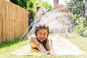 Ein Mädchen kühlt sich an einem Wassersprinkler.